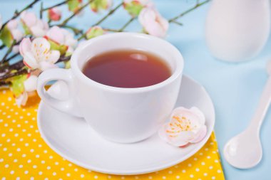 Masada sakura çiçekleri olan bir fincan çay ve kiraz çiçeği. Bahar konsepti