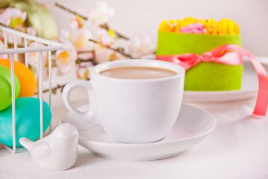 Bir fincan çay, küçük bahar pastası, sakura çiçekleri, Paskalya günü için renkli yumurtalar. Bahar konsepti