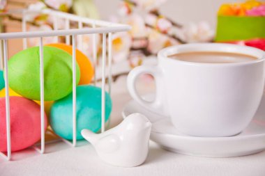 Bir fincan çay, küçük bahar pastası, sakura çiçekleri, Paskalya günü için renkli yumurtalar. Bahar konsepti