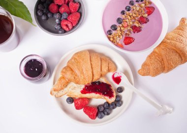 Taze kruvasan çörekleri, böğürtlenler, beyaz arka planda siyah frenk üzümü reçeli. Kahvaltı konsepti. Üst görünüm.