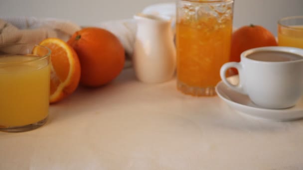Mão de mulher colocar um prato com croissants frescos pães na mesa. Laranjas próximas, compota de laranja e suco. Conceito de pequeno almoço . — Vídeo de Stock