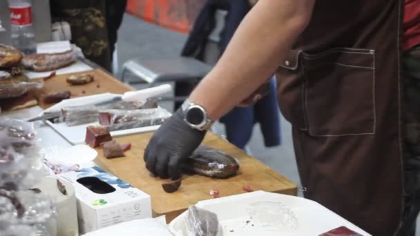 Чоловічі руки розрізали ковбасу на дерев'яній обробній дошці — стокове відео