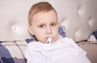 Dijital termometresi olan hasta çocuk. Hasta çocuk vücut ısısını ölçüyor ve kendini iyi hissetmiyor..