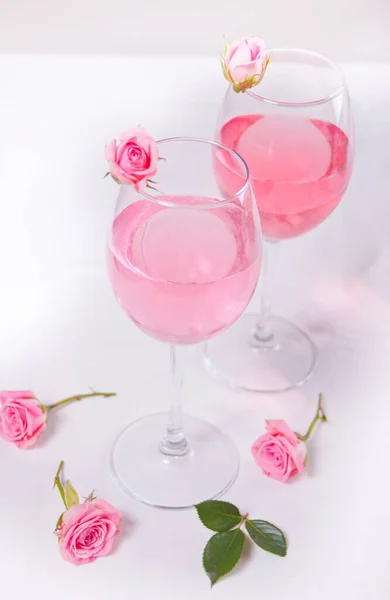 Two glasses with pink grape wine with flowers. Romantic dinner concept