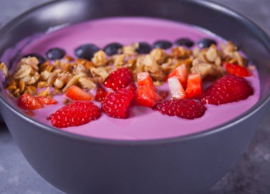 Meyveli meyve suyu kasesi ve gri masada müsli.