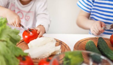 Mutlu çocuklar ev mutfağında salata için sebze hazırlar. Sağlıklı beslenme