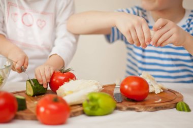 Mutlu çocuklar ev mutfağında salata için sebze hazırlar. Sağlıklı beslenme
