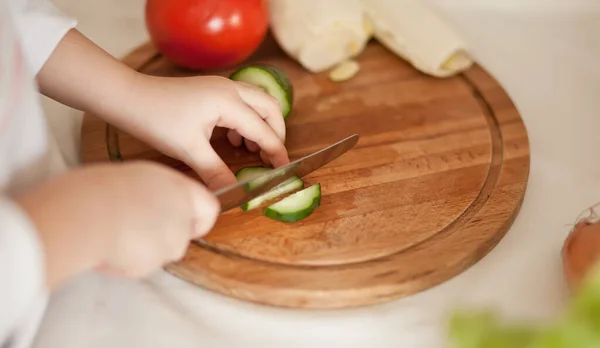Kid child prepares vegetables for salad in home kitchen. Healthy eating