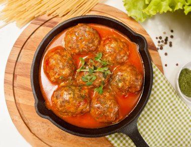 Baharatlı domates soslu köfte ve demir tavada otlar..