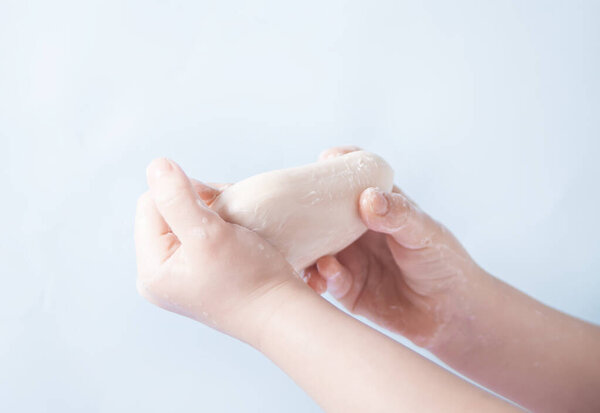 Child washing hands with a bar of white soap. Morning routine