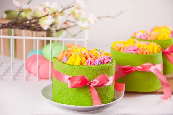 春天复活节餐桌 背景上有奶油奶油花和彩蛋的绿色小蛋糕 — 图库照片