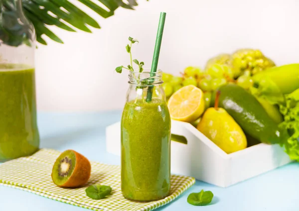 背景に果物や野菜を入れたグラス小瓶の中の新鮮なブレンドグリーンスムージー 健康とデトックスの概念 — ストック写真