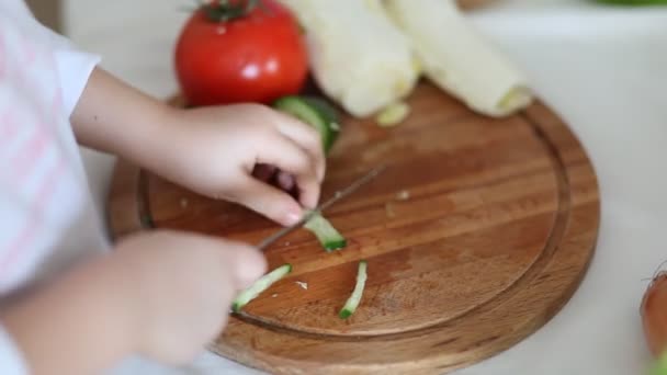 Schattig krullend meisje bereidt groenten voor salade in huis keuken. Gezond eten. — Stockvideo