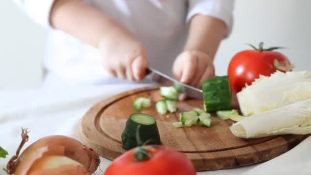 Şirin kıvırcık kız ev mutfağında salata için sebze hazırlıyor. Sağlıklı beslenme. — Stok video