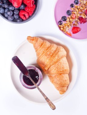 Taze kruvasan çörekleri, böğürtlen, siyah frenk üzümü reçeli ve meyve suyu kasesi. Kahvaltı konsepti. Üst görünüm.