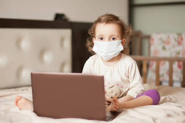 의료용 마스크를 침대에 앉아서 디지탈 태블릿 노트북 노트북 노트북을 사용하는 — 스톡 사진
