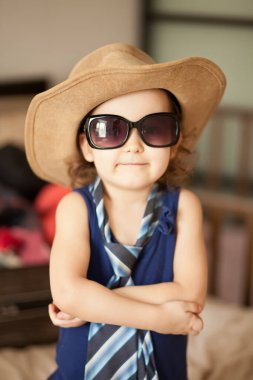 Mutlu bir çocukluk. Büyük kovboy şapkası ve güneş gözlüğü takan şirin bir kız. Sevimli çocuk içeride eğleniyor.