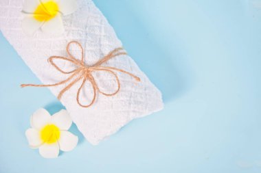 Bakım, güzellik ve kaplıca konsepti. Beyaz havlu ve Plumeria Frangipani çiçeği. Uzayı kopyala Üst görünüm