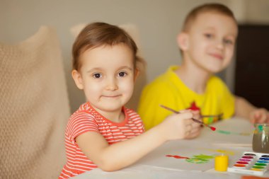 Kağıtlara renkli boyalar çizen bir çocuk.