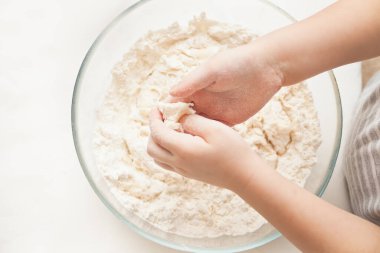 Küçük çocuk mutfakta pizza ya da başka bir yemek için hamur hazırlıyor. Üst görünüm