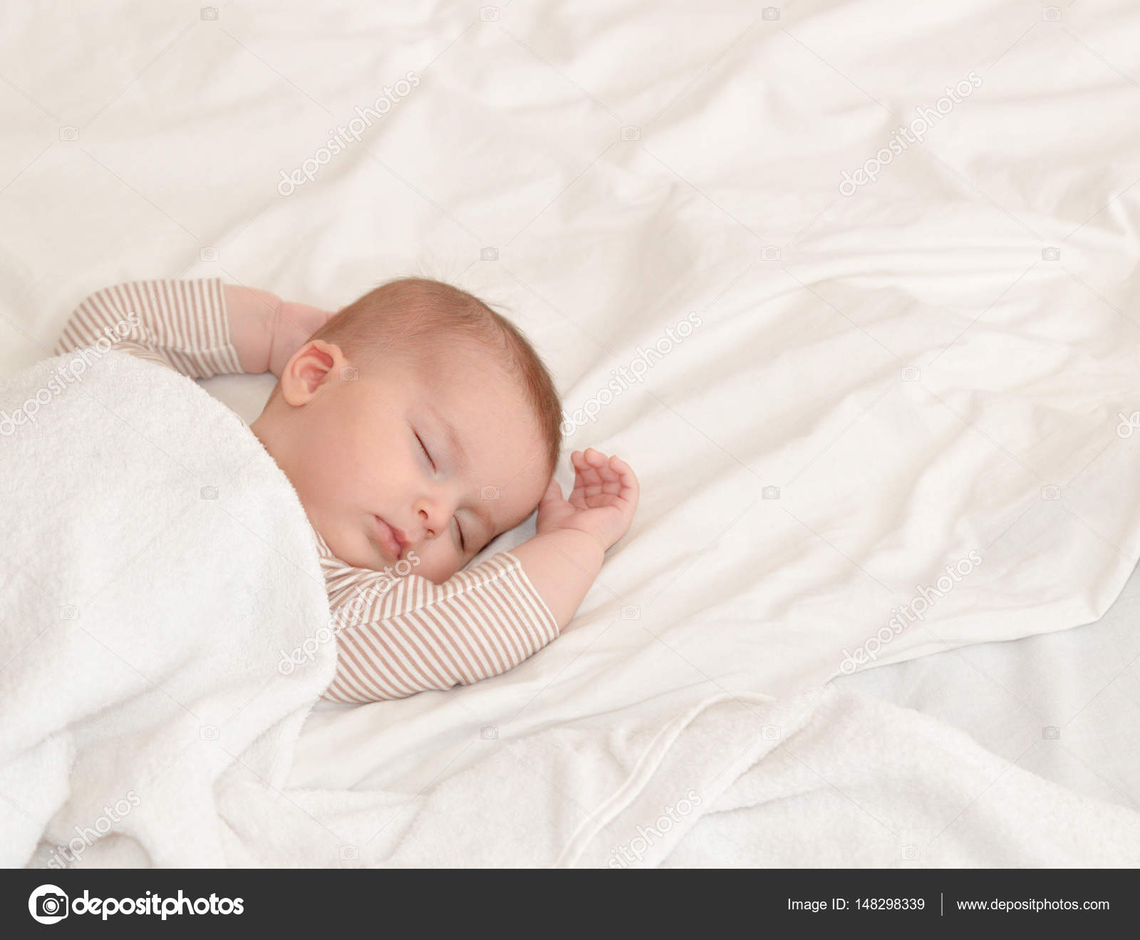 Peaceful baby lying on a bed while sleeping in a bright room ⬇ Stock