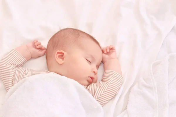 Bebê tranquilo deitado em uma cama enquanto dorme em um quarto brilhante — Fotografia de Stock