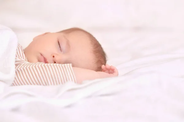 Bebé tranquilo acostado en una cama mientras duerme en una habitación luminosa —  Fotos de Stock