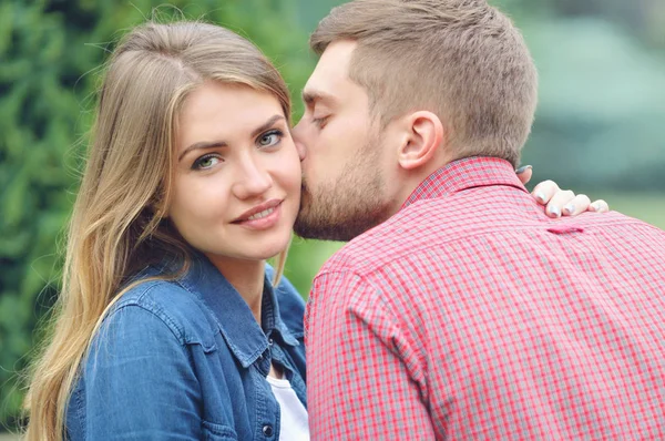 Young beautiful girl staring at camera while being kissed — Stock Photo, Image