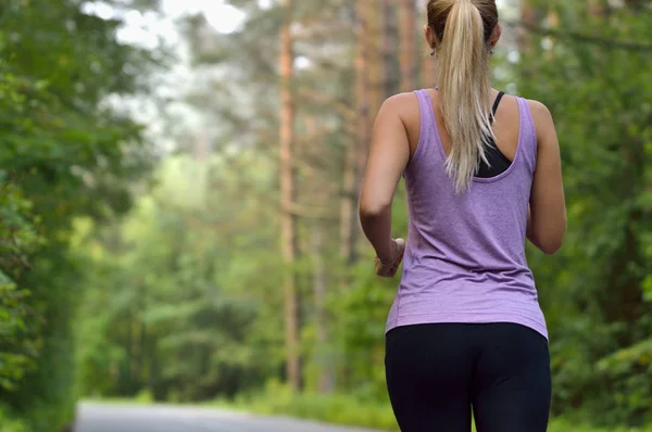 Jonge sportieve sportieve meisje met lang haar opleiding in groen bos tijdens de zomer of herfst seizoen. — Stockfoto