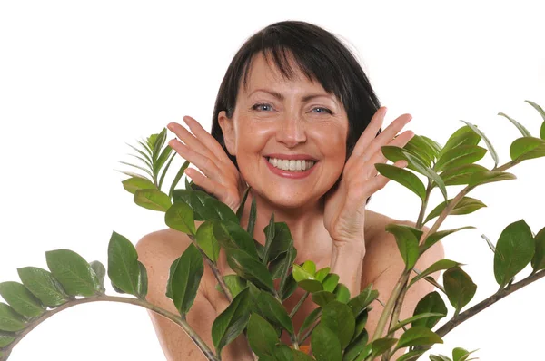 Alegre mujer madura feliz asomarse desde detrás de las flores — Foto de Stock