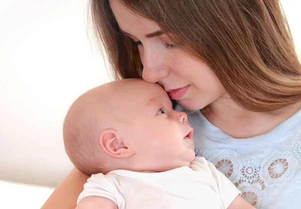 Junge Mutter hält ihr neugeborenes Kind und küsst es — Stockfoto