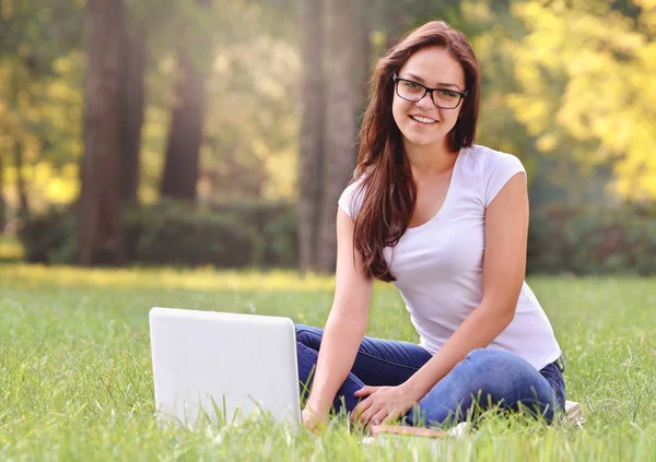 Student girl sitting on the grass in the park — Stock Photo, Image