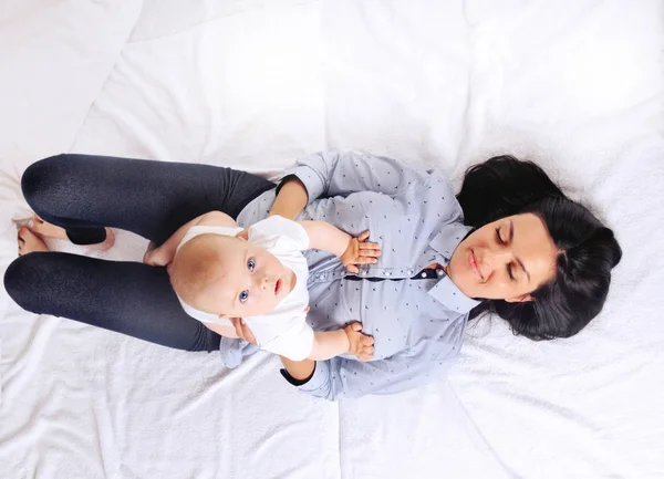 Retrato de la hermosa mamá jugando con su bebé en el dormitorio —  Fotos de Stock