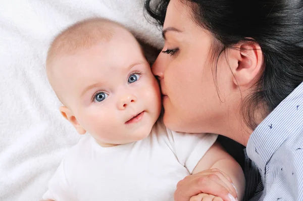 하얀 침대에 그녀의 아들을 키스 하는 엄마 — 스톡 사진