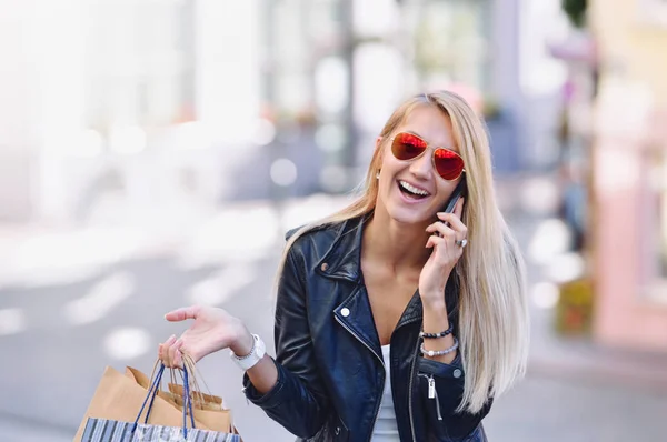 Νεαρή γυναίκα χαμογελαστή με σακούλες μιλήσω μέσω κινητού τηλεφώνου. — Φωτογραφία Αρχείου