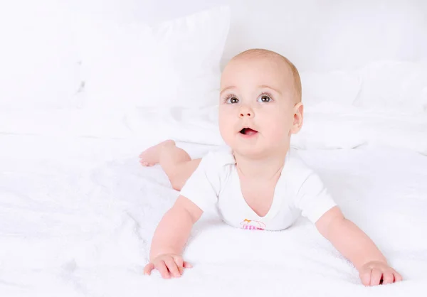 Χαριτωμένο μωρό με όμορφα καστανά μάτια, ξαπλωμένη στο κρεβάτι λευκό — Φωτογραφία Αρχείου