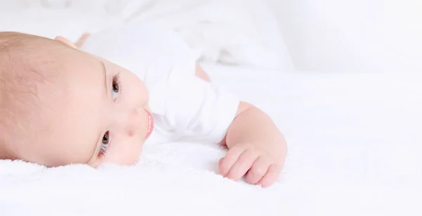 Младенец лежит и счастливо улыбается на одеяле — стоковое фото