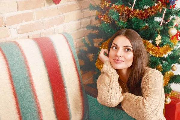 Chica feliz sentarse bajo el árbol de Navidad y soñar —  Fotos de Stock