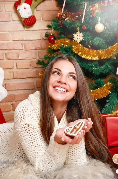 Mujer bonita se acuesta en el suelo bajo el árbol de Navidad y sostiene los regalos en las manos —  Fotos de Stock