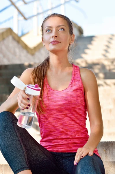 Sportliche Frau ruht sich nach Joggen mit Wasserflasche aus — Stockfoto