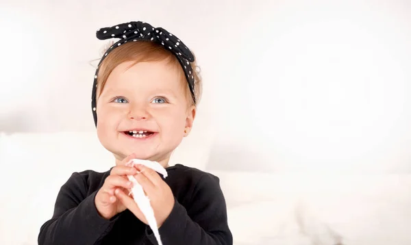 Cute baby girl dressed in a black dress on white light background — Stock Photo, Image