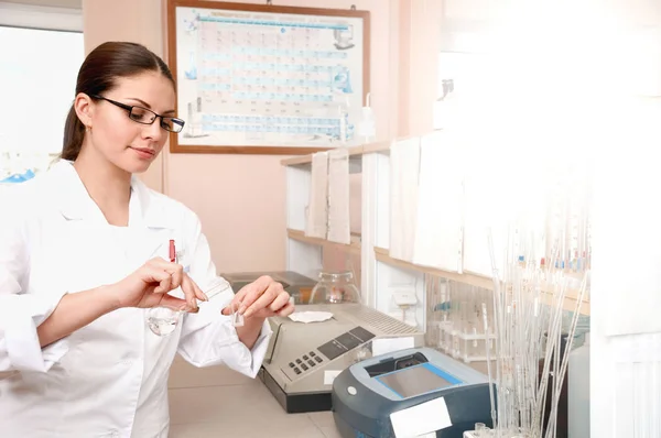 Kvinnliga läkare i vit uniform håller kolvarna medan du arbetar i laboratoriet — Stockfoto