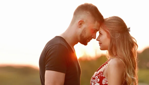 Akşam güneşi genç çift sahada sarılma aydınlatır