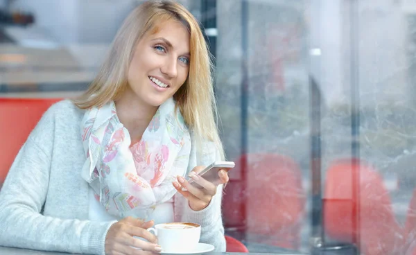 Charmoso feminino feliz ler notícias no telefone celular durante o café da manhã no café — Fotografia de Stock