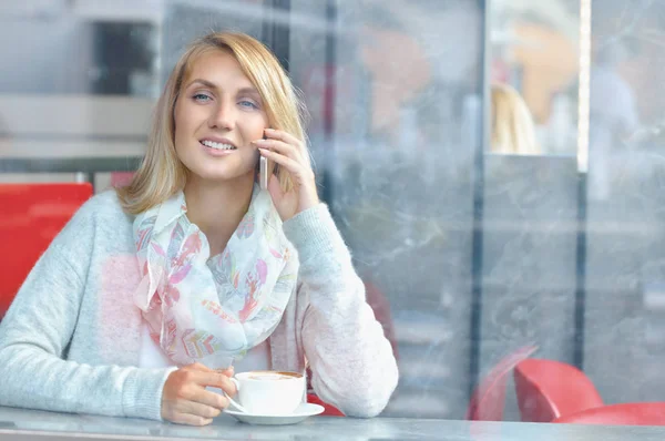 Fiatal nő mosollyal mozgatható telefon beszélgetést, miközben pihen a café — Stock Fotó