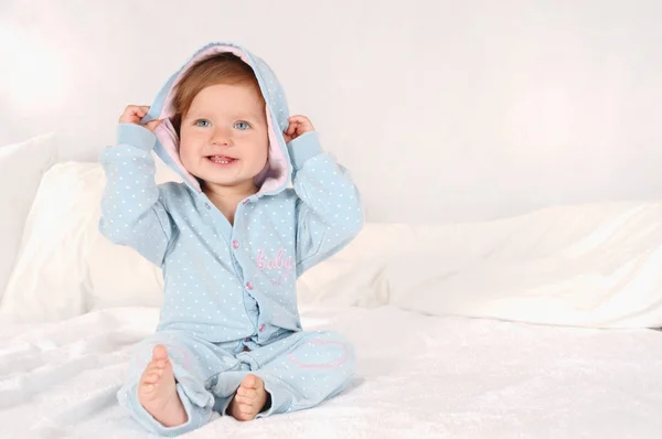 Retrato de una niña sonriente vestida de pijama azul en casa —  Fotos de Stock