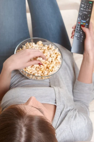 Women watching tv with popcorn at home. Top view