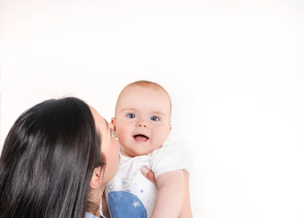ママは白い背景に彼女の息子にキス カメラを見ている新生児幸せな母性の概念 — ストック写真