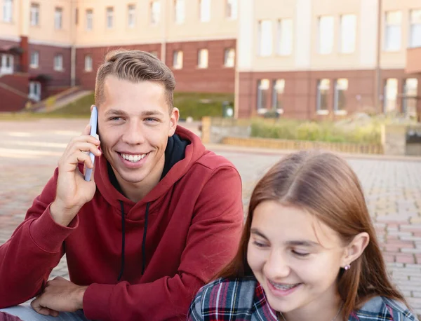 Szczęśliwy Uśmiechnięty Nastolatek Rozmawiający Przez Telefon Grupą Studentów Schodach Pobliżu — Zdjęcie stockowe