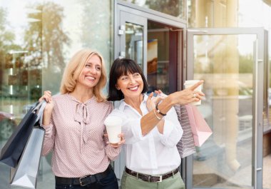 Alışveriş yaparken ve kahve içerken eğlenen iki olgun kadın. Yetişkin insanların eğlence anlayışı